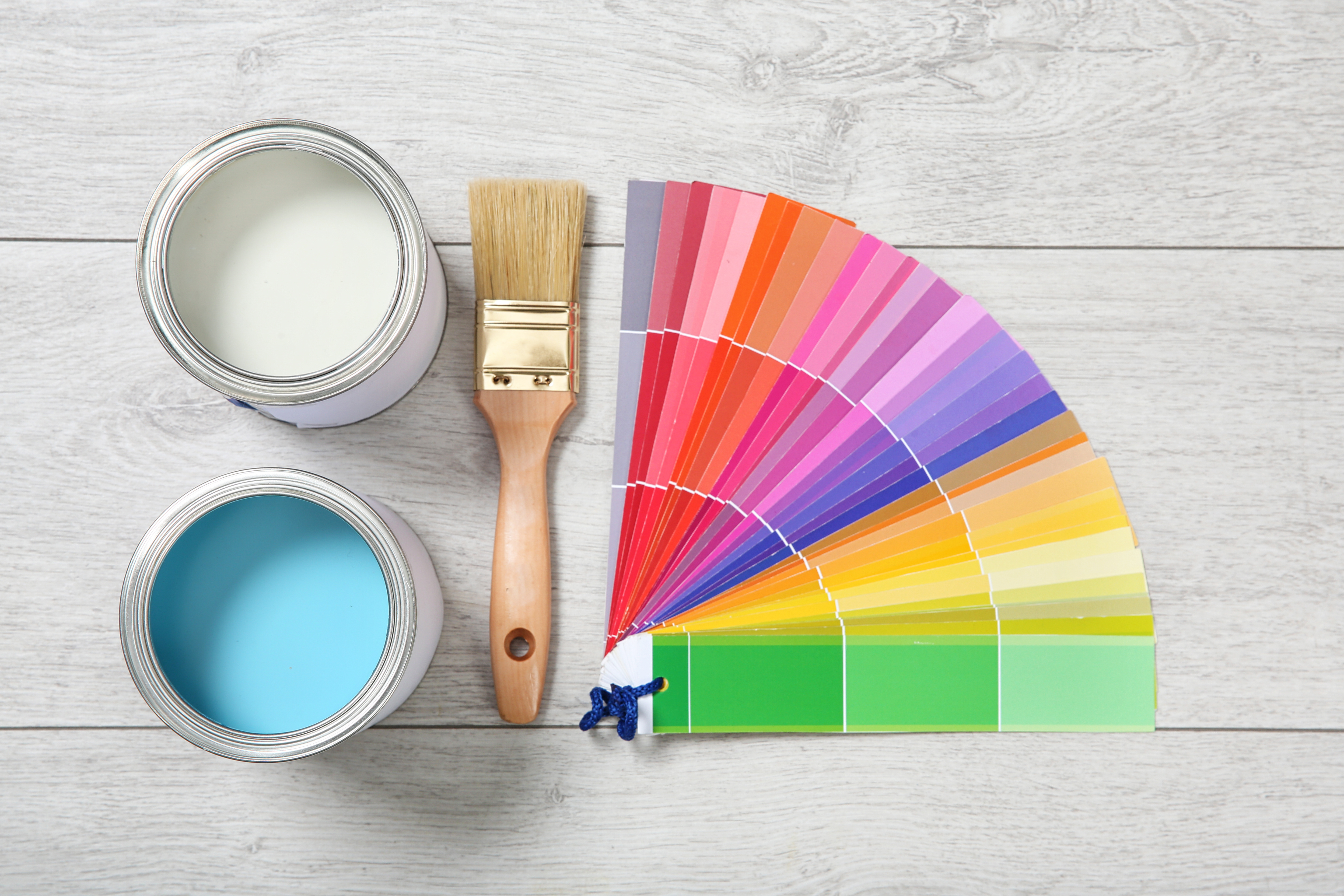 Flat lay composition with cans of paint and decorator tools on wooden background