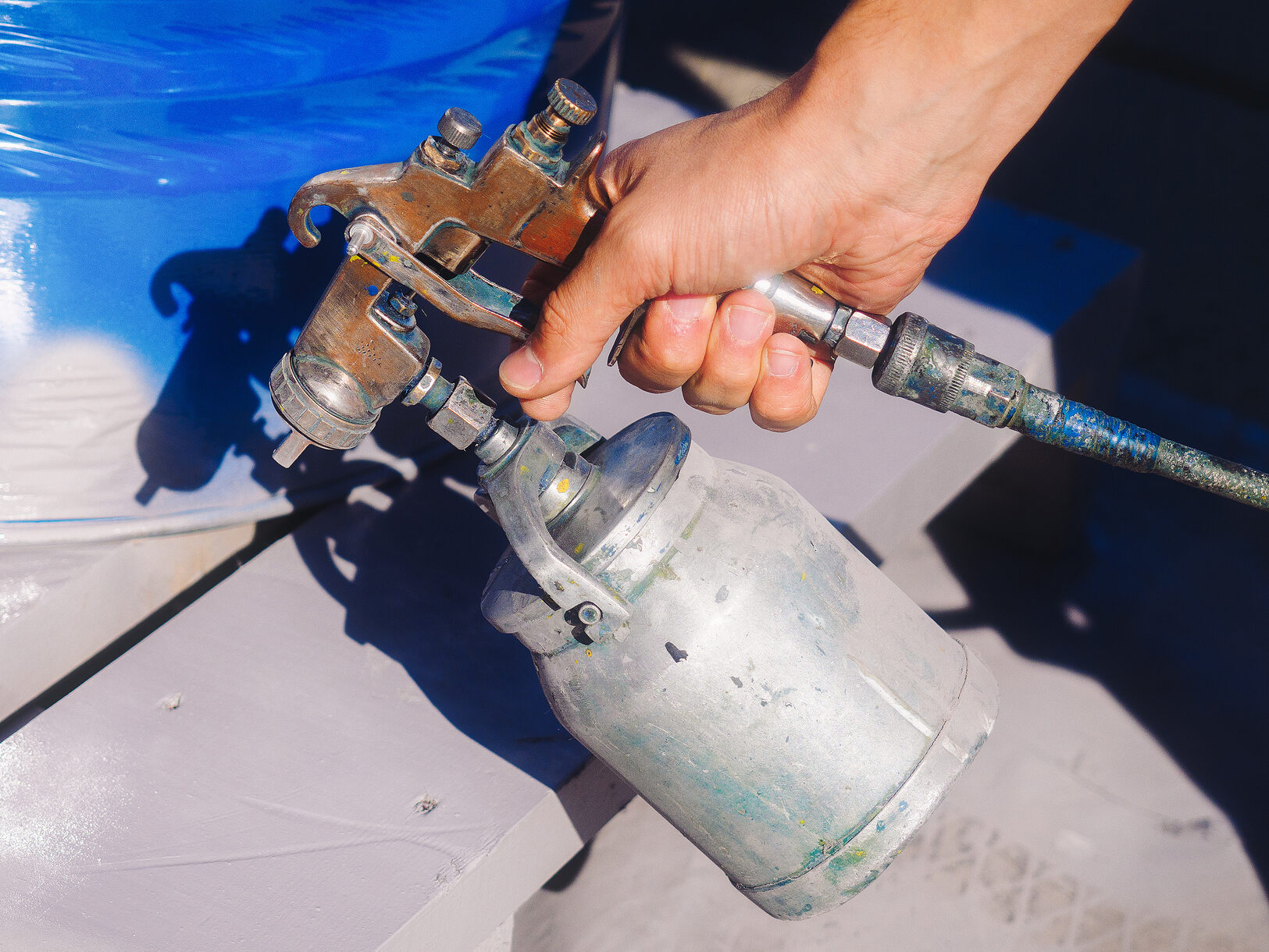 Hand painter with gun sprayer close-up. Professional coloring. Background